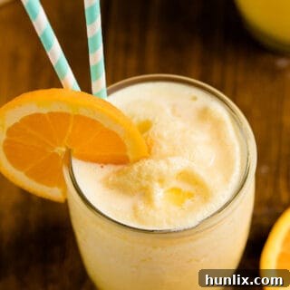 The recipe in a glass with a straw and orange slice on a wooden surface.