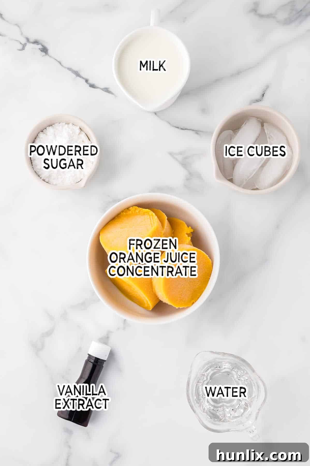 Ingredients for Orange Julius on a white marble counter.