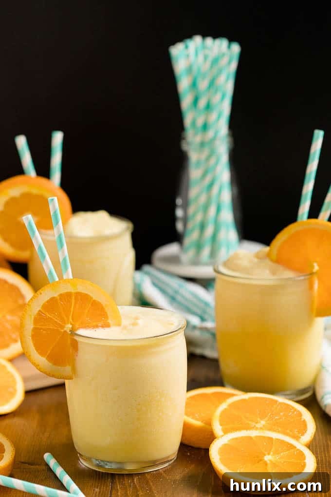 The Orange Julius recipe in a glass cup with straws and an orange slice.