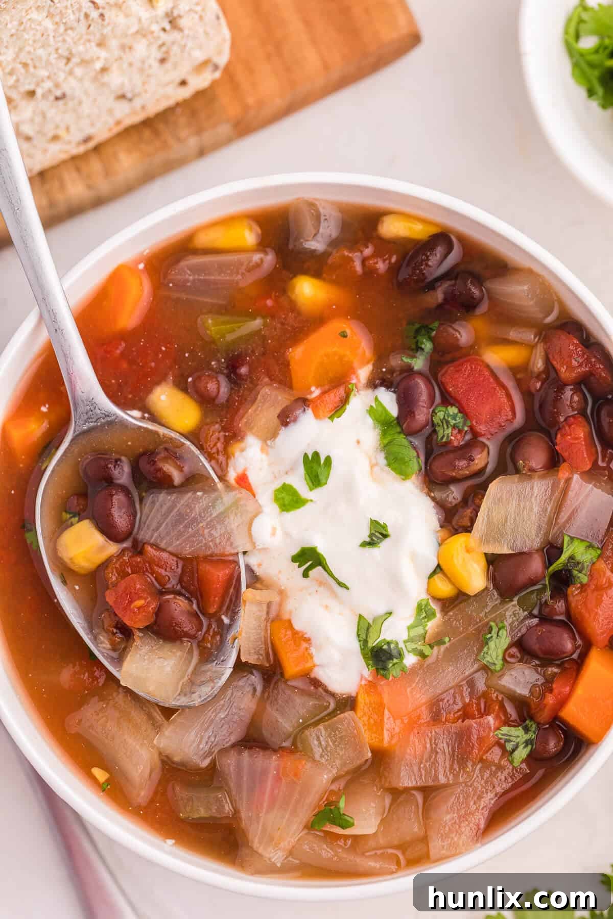 A close-up of a bowl of Black Bean Vegetable Soup, garnished with green herbs and a slice of lime, showcasing its rich texture.