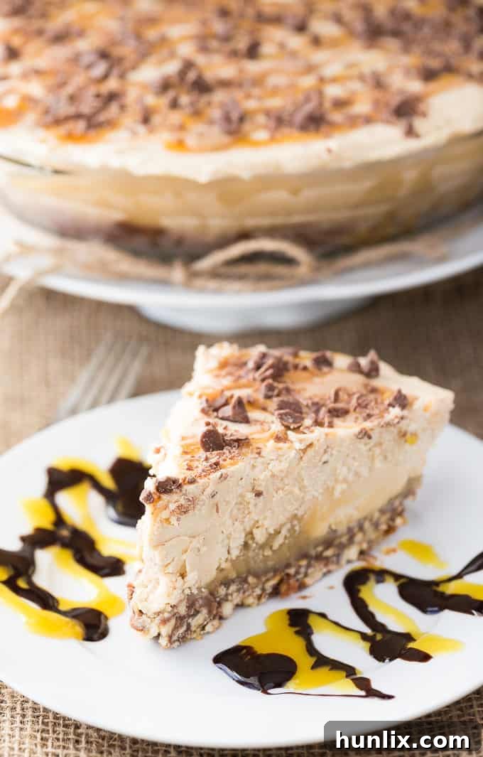 No Bake Peanut Butter Dream Pie 4 Close-up shot of a slice of Frozen Peanut Butter Pie, highlighting the distinct layers of pretzel crust, chocolate, caramel, and the fluffy peanut butter filling.