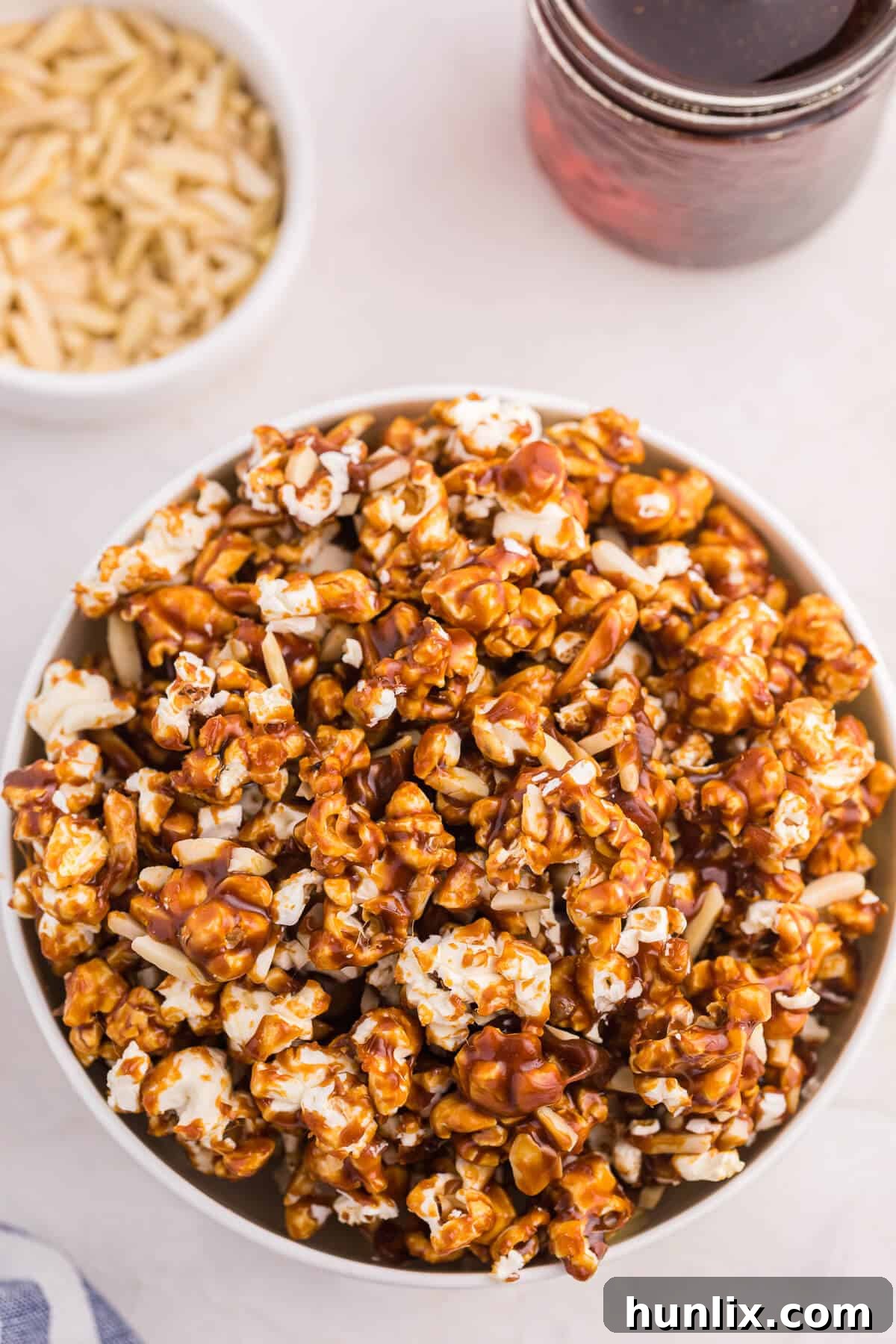 Maple-Glazed Almond Popcorn 2 A large, rustic bowl overflowing with golden Maple Almond Popcorn, featuring perfectly glazed kernels and visible slivered almonds.
