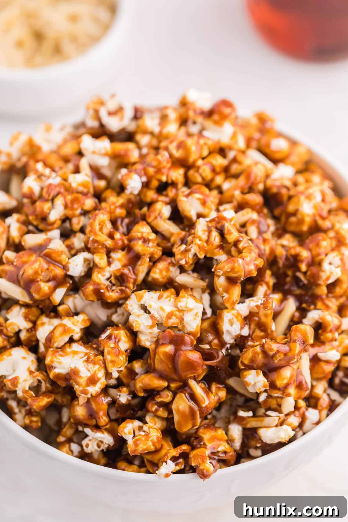 Maple-Glazed Almond Popcorn 4 A large, inviting bowl filled to the brim with homemade Maple Almond Popcorn, featuring a generous coating and crunchy almonds, ready for sharing.