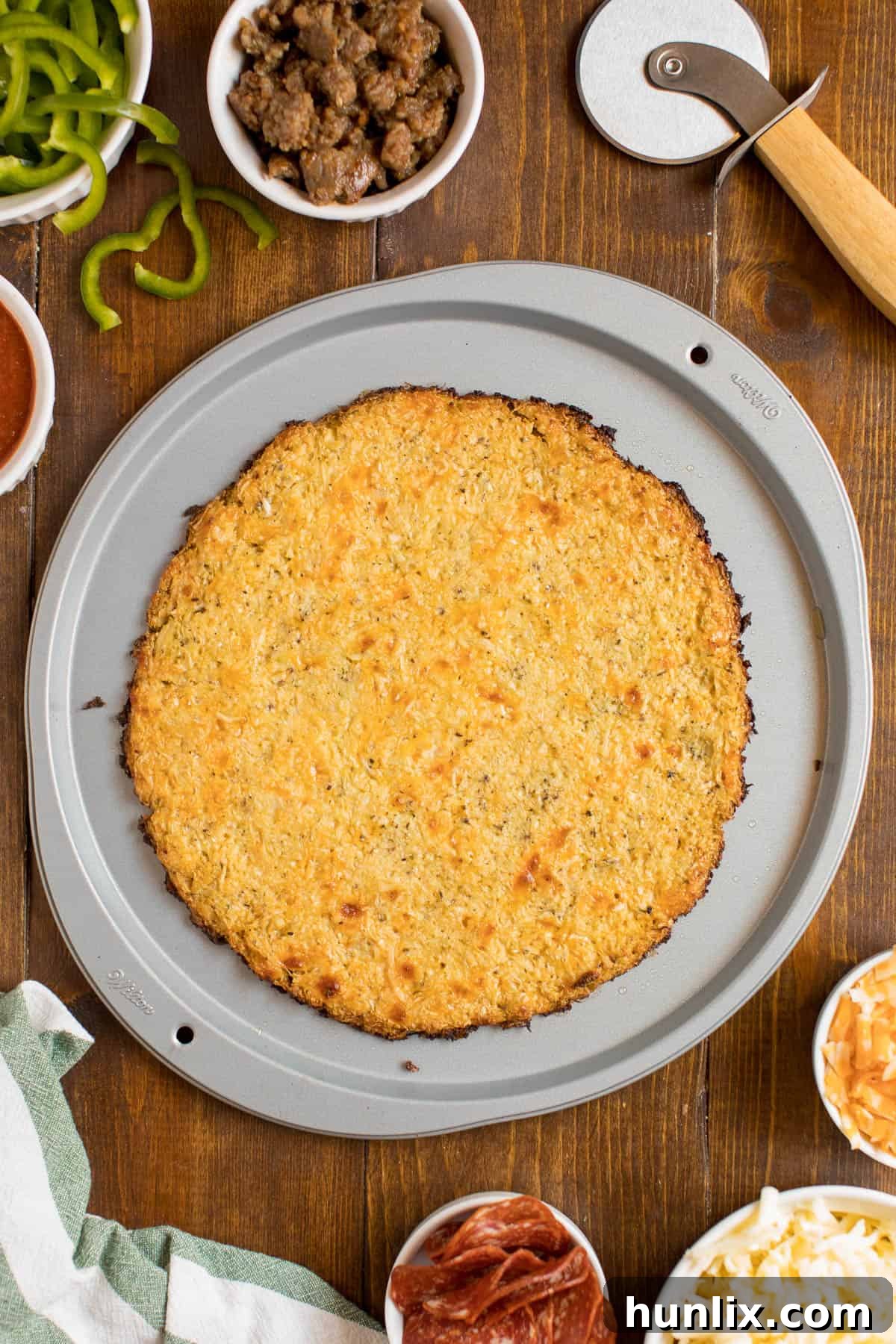 A freshly baked cauliflower pizza crust on a pizza pan, ready for toppings.