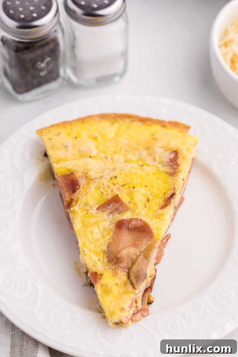 Hearty Turkey Bacon Frittata 6 A slice of Turkey Bacon Frittata on a plate, garnished with fresh herbs, alongside a side salad, showcasing a complete meal idea.