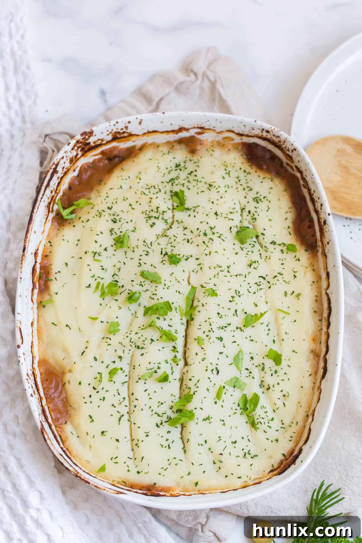 Beef Picadillo Shepherd's Pie on a white surface, showcasing a rich, savory filling topped with golden cauliflower mash.