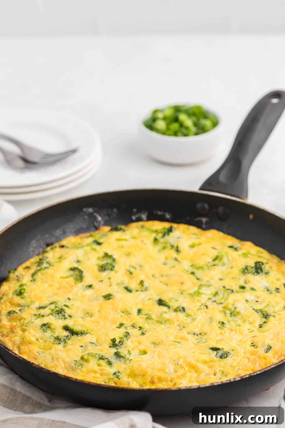 Savory Broccoli Frittata 2 A vibrant green and yellow broccoli frittata nestled in a pan, ready to be served, showcasing its fluffy texture.