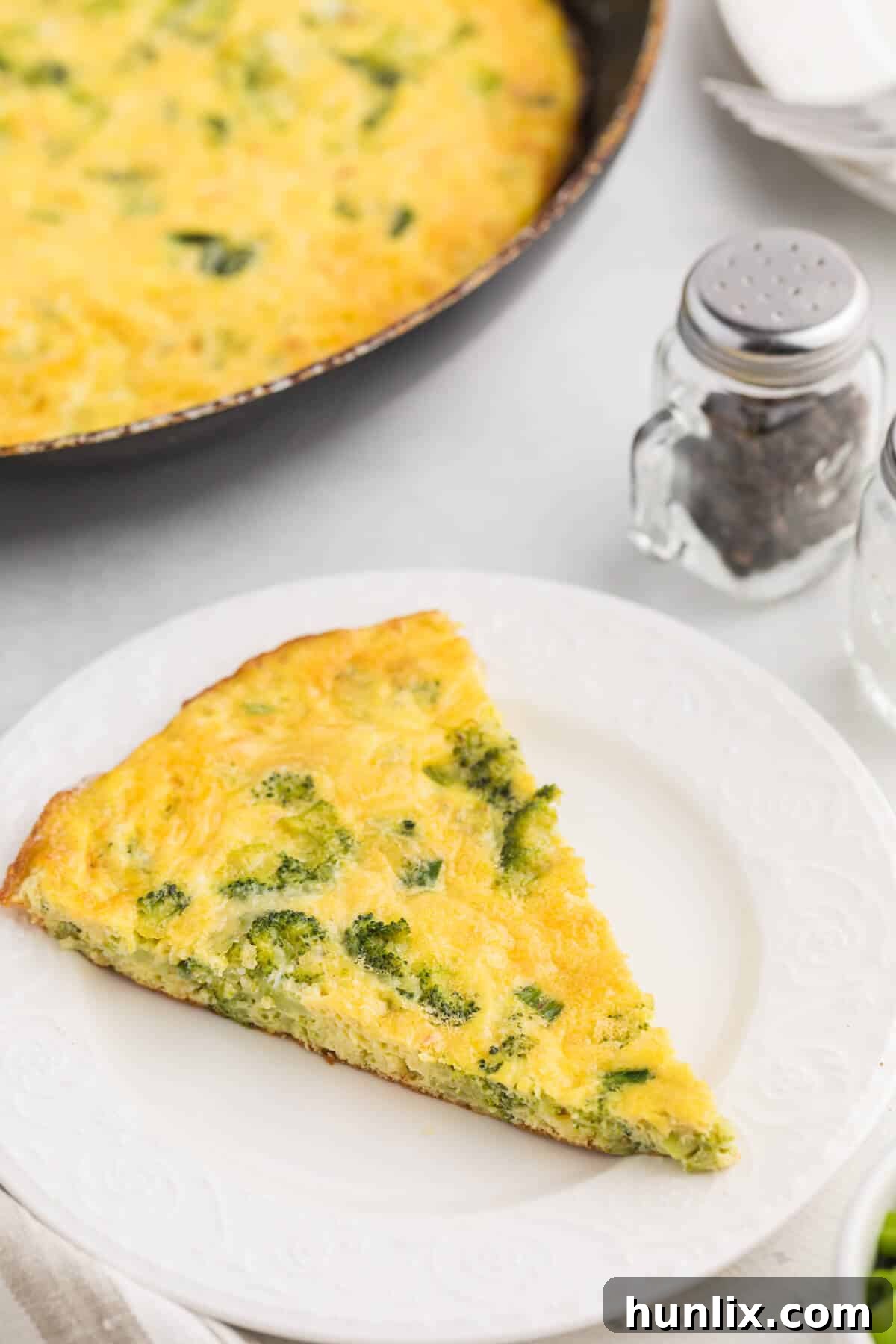 Savory Broccoli Frittata 7 A vibrant slice of broccoli frittata on a white plate, showcasing its golden-brown edges and fluffy texture.