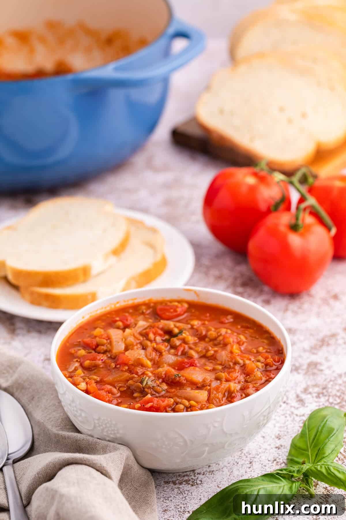 A generous serving of tomato lentil soup in a rustic bowl, with a sprig of fresh herbs for garnish.