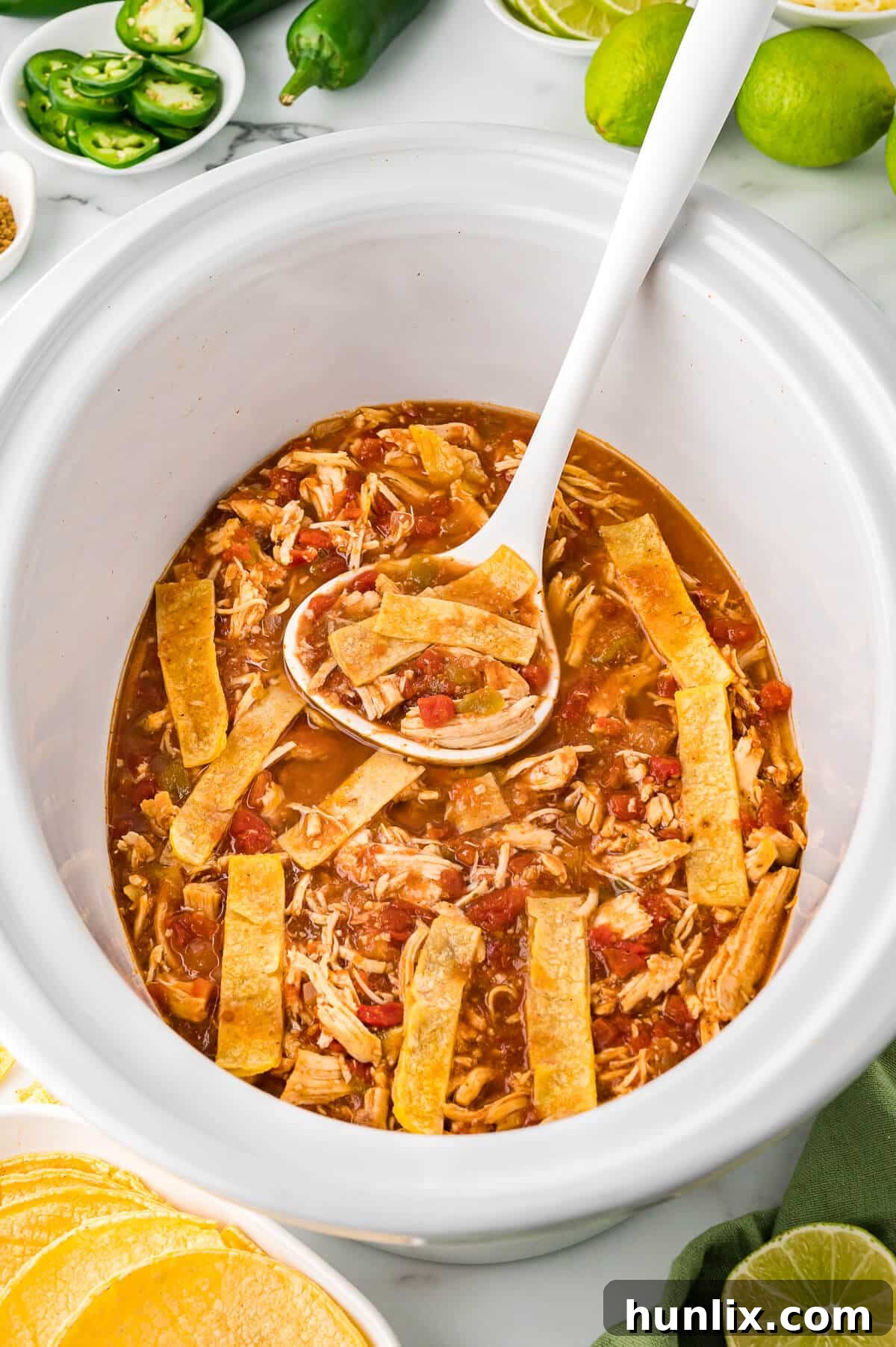 Fiesta Chicken Tortilla Soup 6 The finished chicken tortilla soup in a white slow cooker with a white ladle.