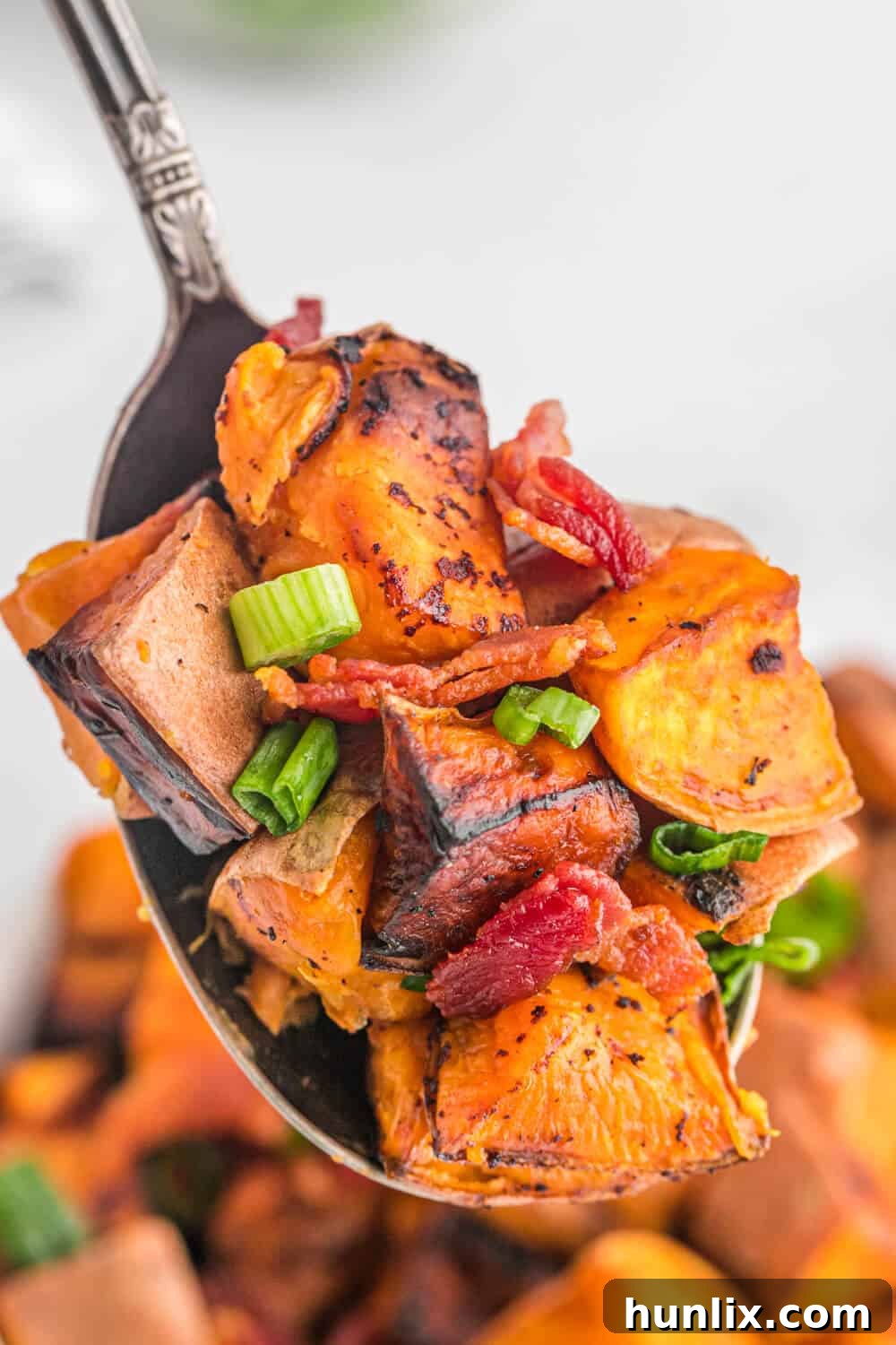 A serving of sweet potato home fries on a spoon.