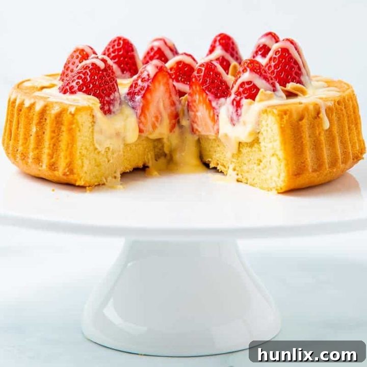 Impressive Strawberry Flan with a sponge base, vanilla custard, fresh strawberries, and white chocolate drizzle.