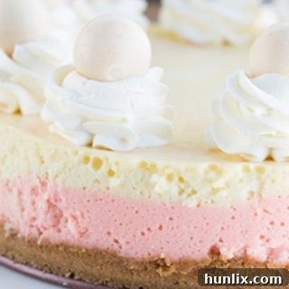 Strawberries and Cream Cheesecake with a cookie crumb crust, strawberry cheesecake layer, and a vanilla layer, plus a truffle surprise.