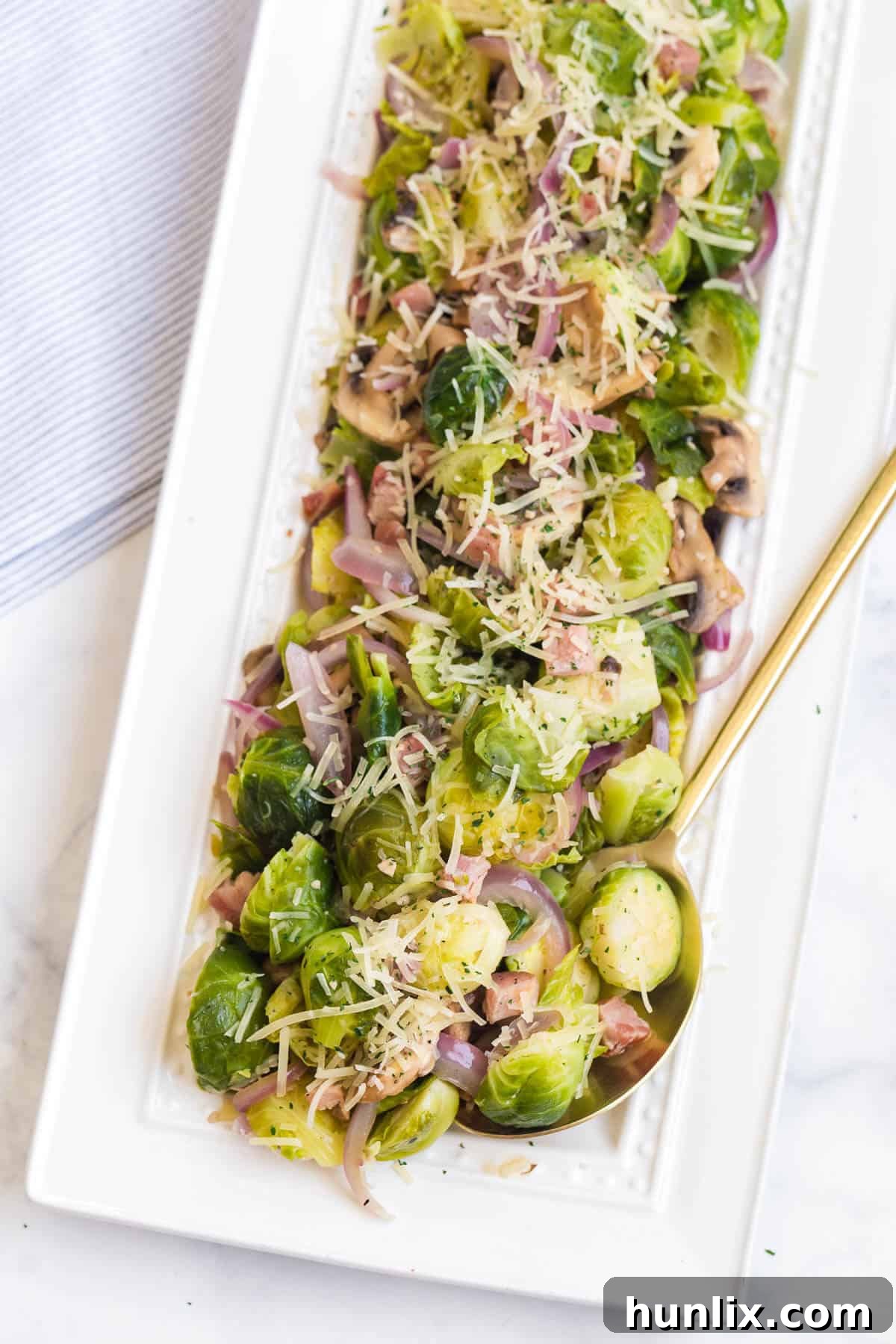 A platter of beautifully pan-fried Brussels sprouts with golden-brown crispy pancetta and fresh lemon wedges, ready to be served.