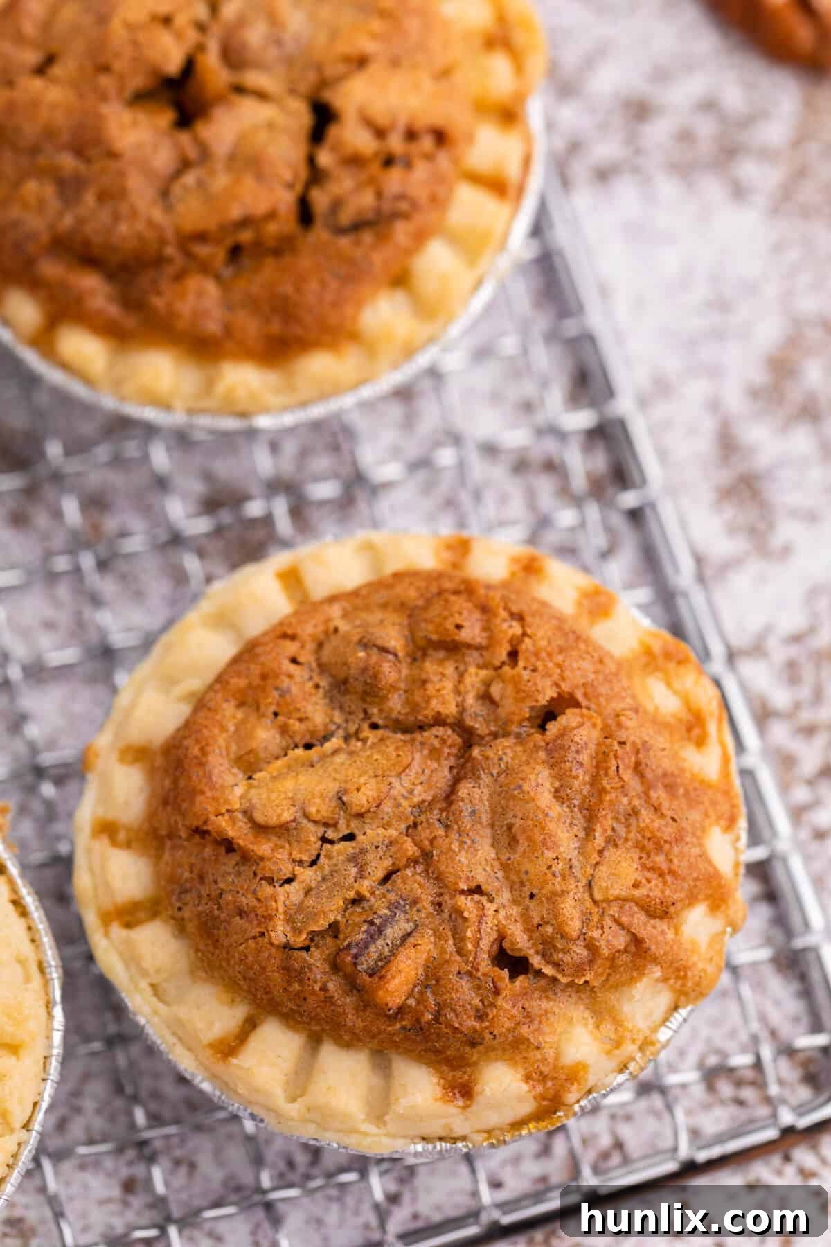 A single pecan butter tart on a wire rack, showcasing its golden crust and gooey filling.