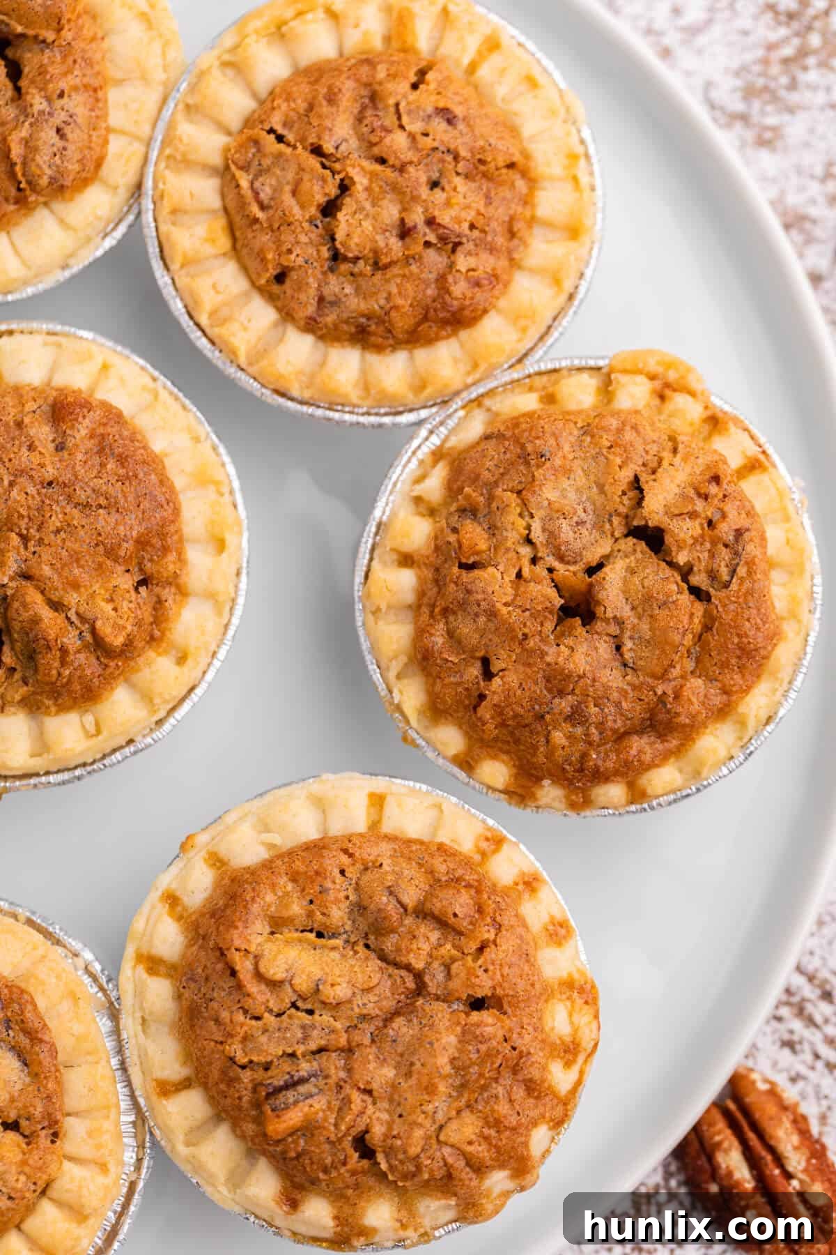 Freshly baked pecan butter tarts arranged on a white plate, ready to be served.