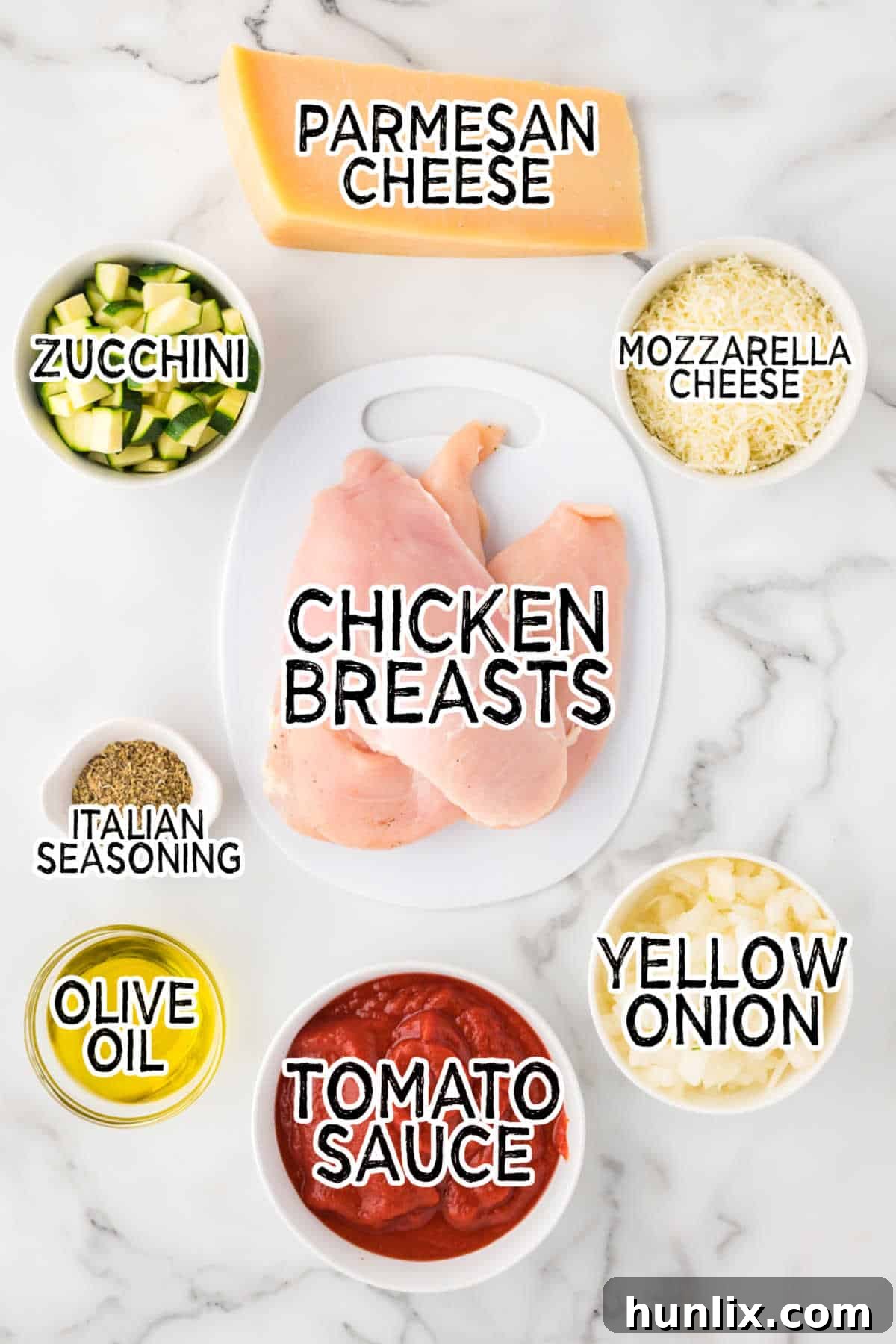 Homestyle Chicken Parmesan Bake 3 Fresh ingredients laid out for making Baked Chicken Parmesan, including chicken breasts, zucchini, onion, tomato sauce, and cheeses.