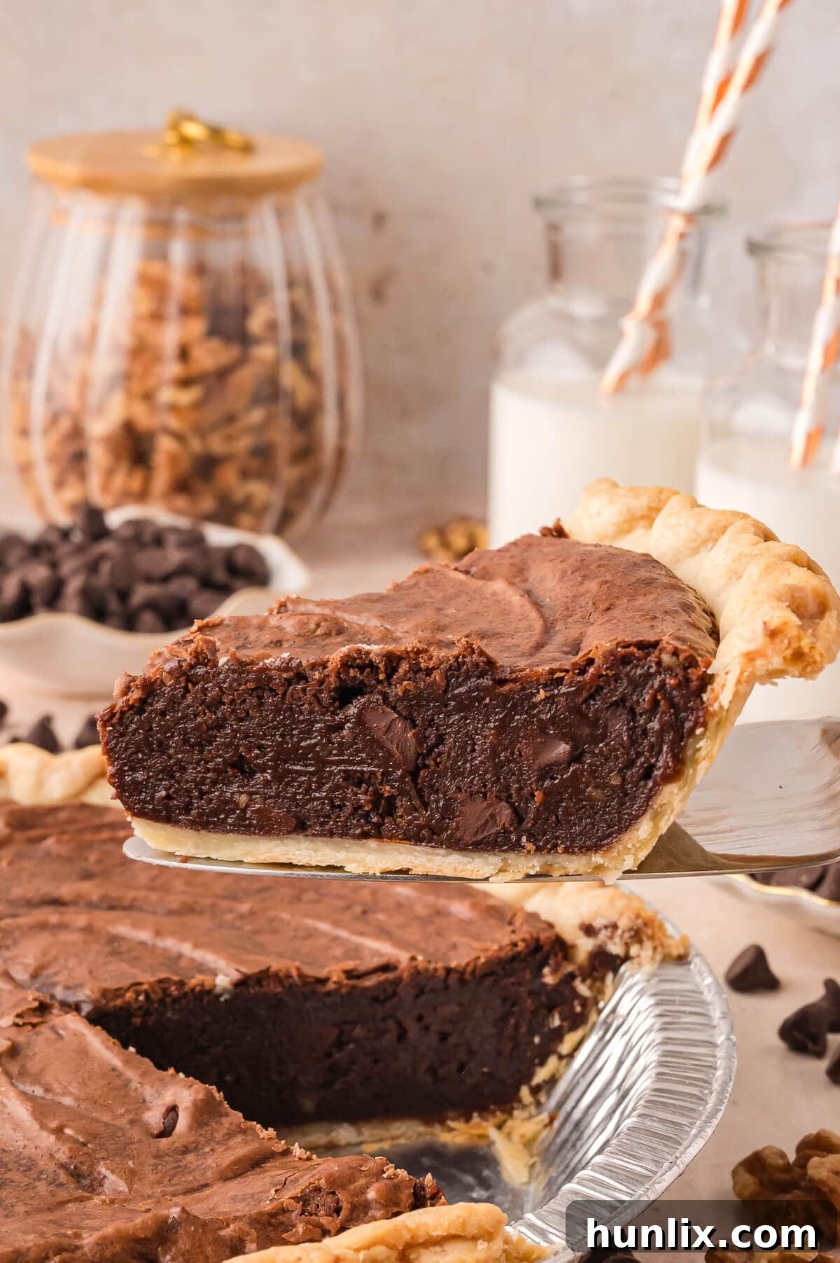A slice of warm, fudgy Brownie Pie being lifted from the pie plate with a pie server, showcasing its rich texture and golden crust.
