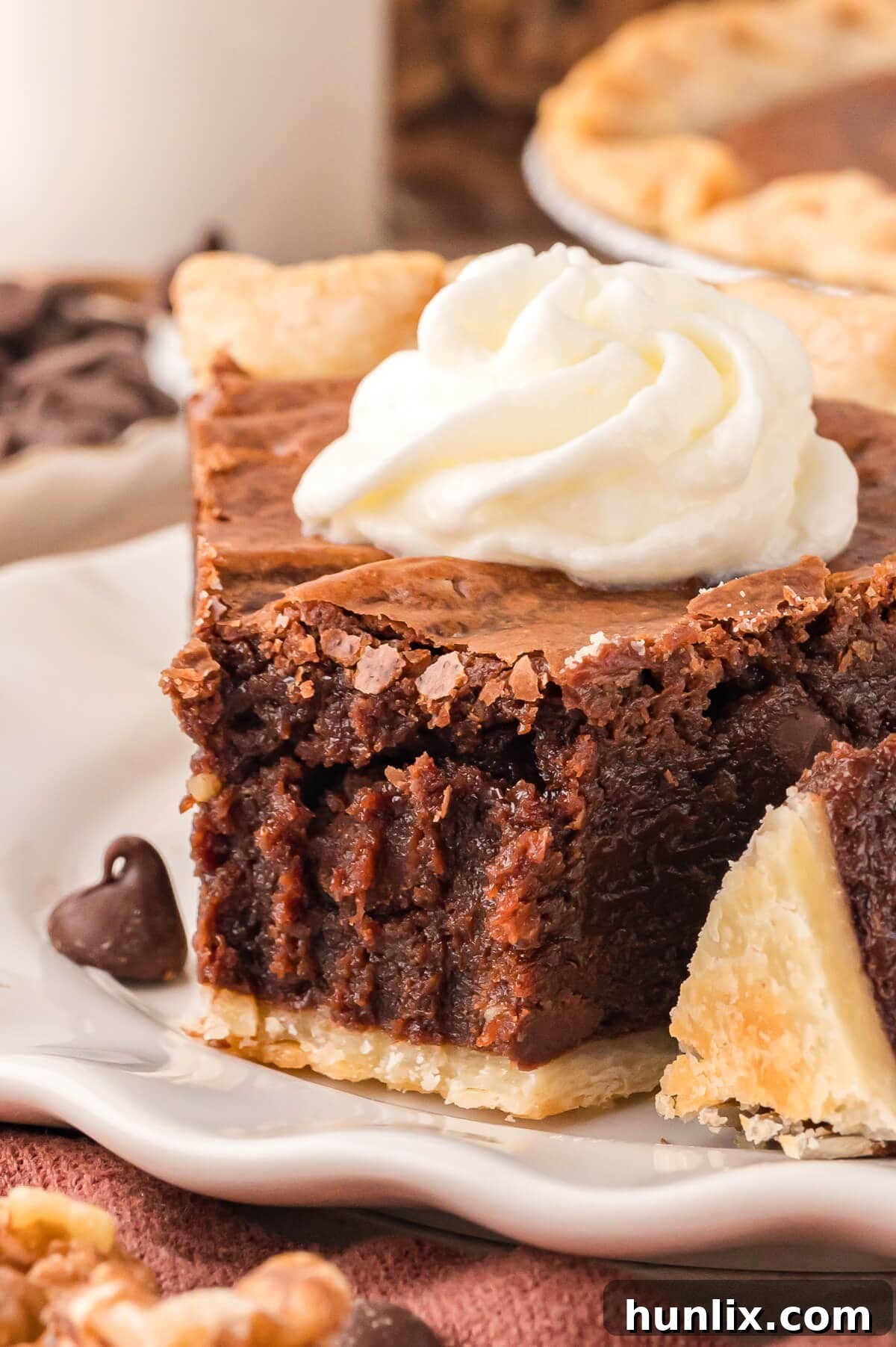 A close-up of a slice of fudgy Brownie Pie on a white plate, with a bite taken from the edge, revealing its moist and rich interior.