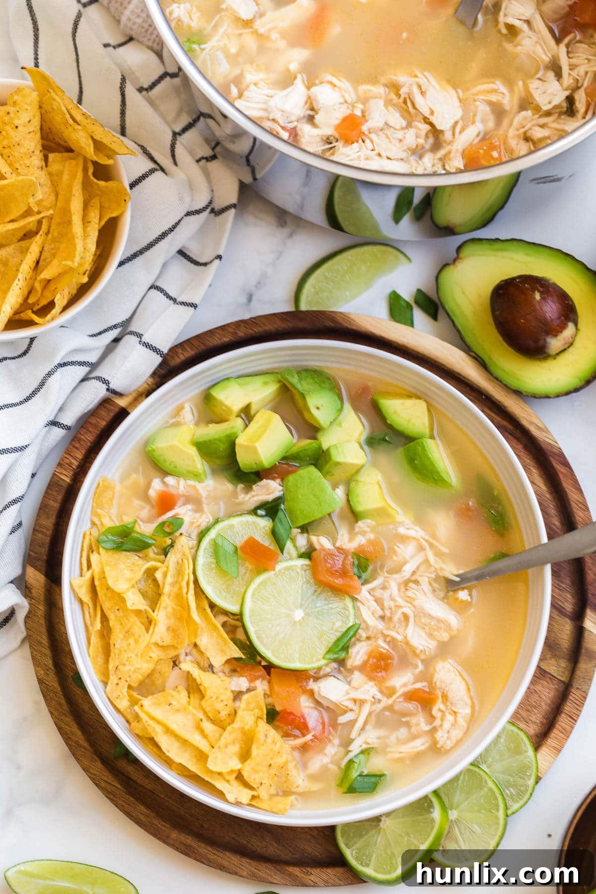A close-up of Chicken and Lime Soup in a bowl, with a spoon revealing the tender chicken and fresh garnishes.