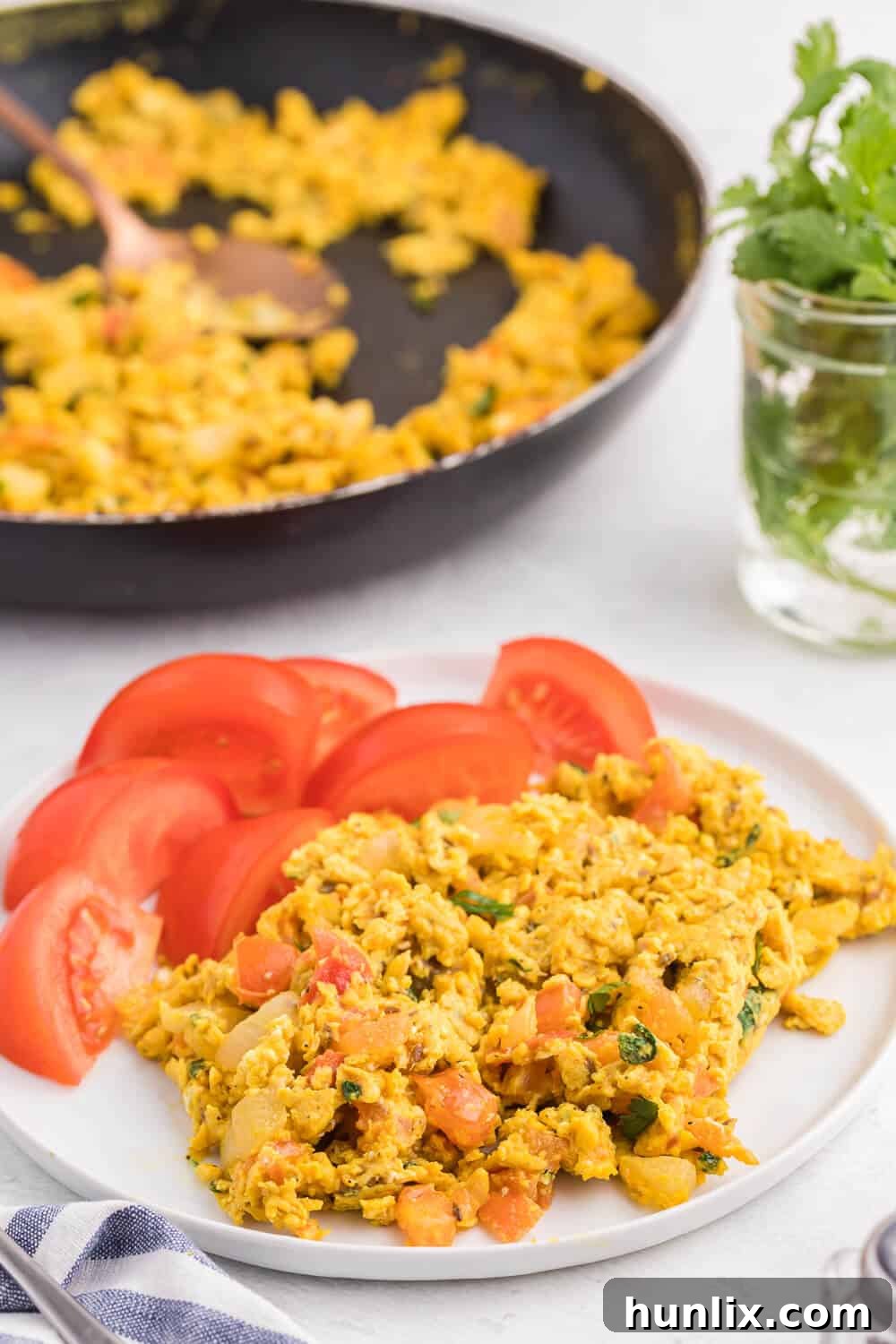 A bowl of Indian Scrambled Eggs with a fork, ready to be eaten. The vibrant colors and creamy texture are clearly visible.