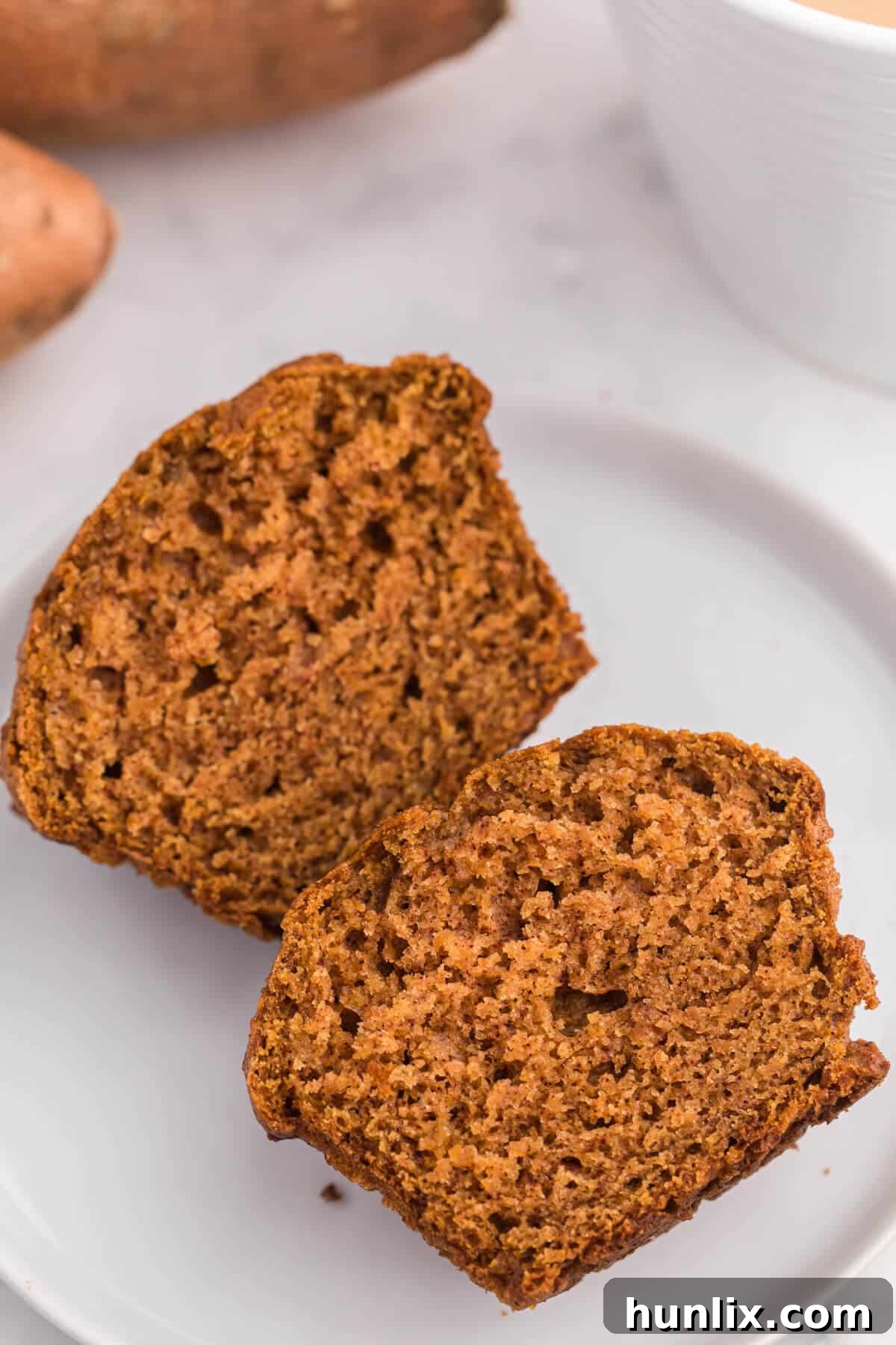 A sweet potato muffin cut in half on a plate, revealing its moist, tender interior and inviting texture, perfect for a close-up.