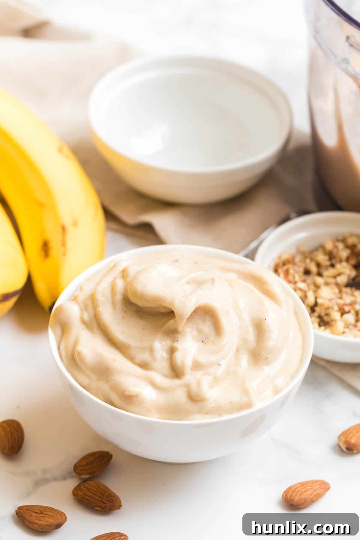 Dairy-free banana ice cream served in a white bowl, garnished with almonds