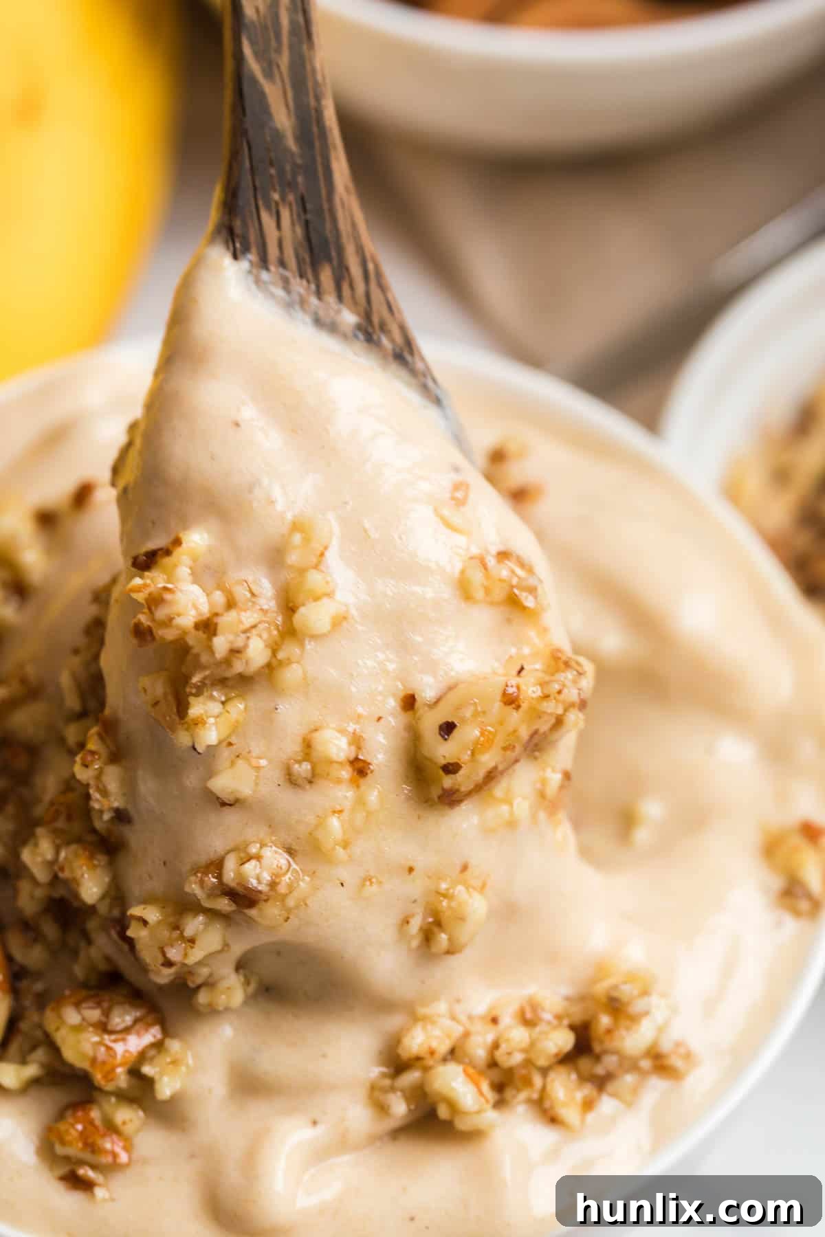 A scoop of dairy-free banana ice cream on a spoon from a bowl