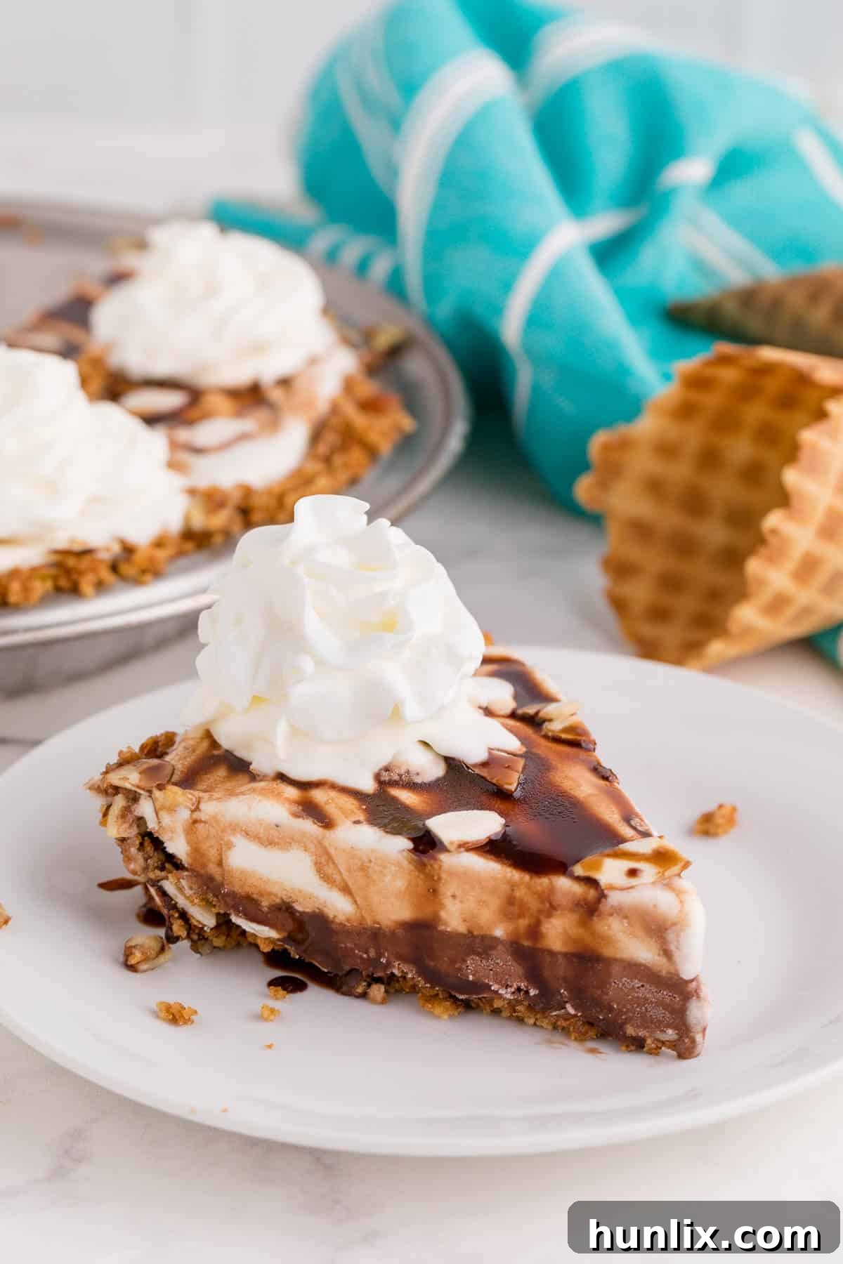 A perfectly portioned slice of ice cream pie on a white plate, showcasing its distinct layers and appealing texture.