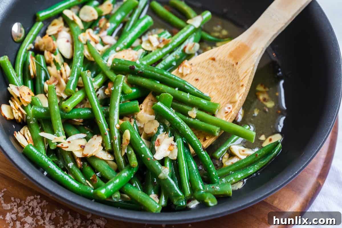 Buttery Chili Green Beans with Toasted Almonds 5 Close-up of chili buttered green beans and almonds, perfectly coated and glistening, in a skillet.