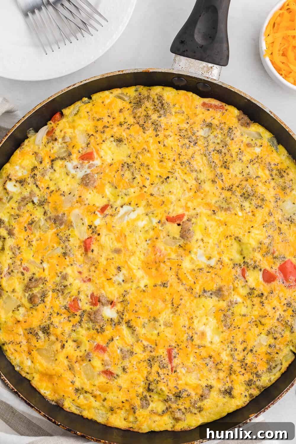 Close-up of a skillet filled with Sausage & Red Pepper Frittata, showing the vibrant colors of the ingredients and the fluffy egg texture. Ready to be sliced and served.