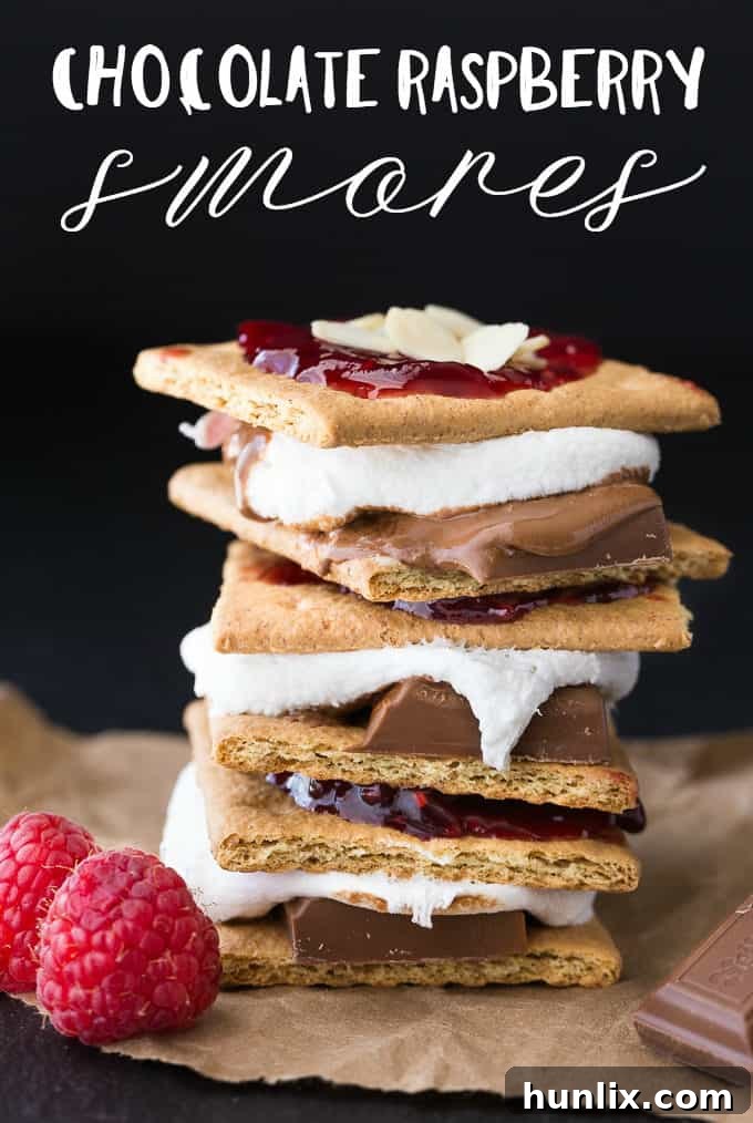Indoor Chocolate Raspberry S'mores with melted marshmallow and chocolate, garnished with fresh raspberries and almonds.