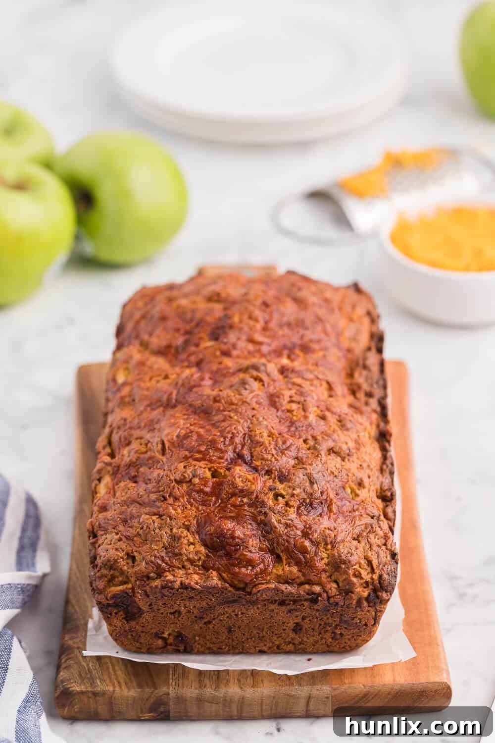 Tangy Cheddar and Sweet Apple Quick Bread 2 A beautifully baked loaf of Apple Cheddar Quick Bread on a rustic cutting board, ready to be sliced.