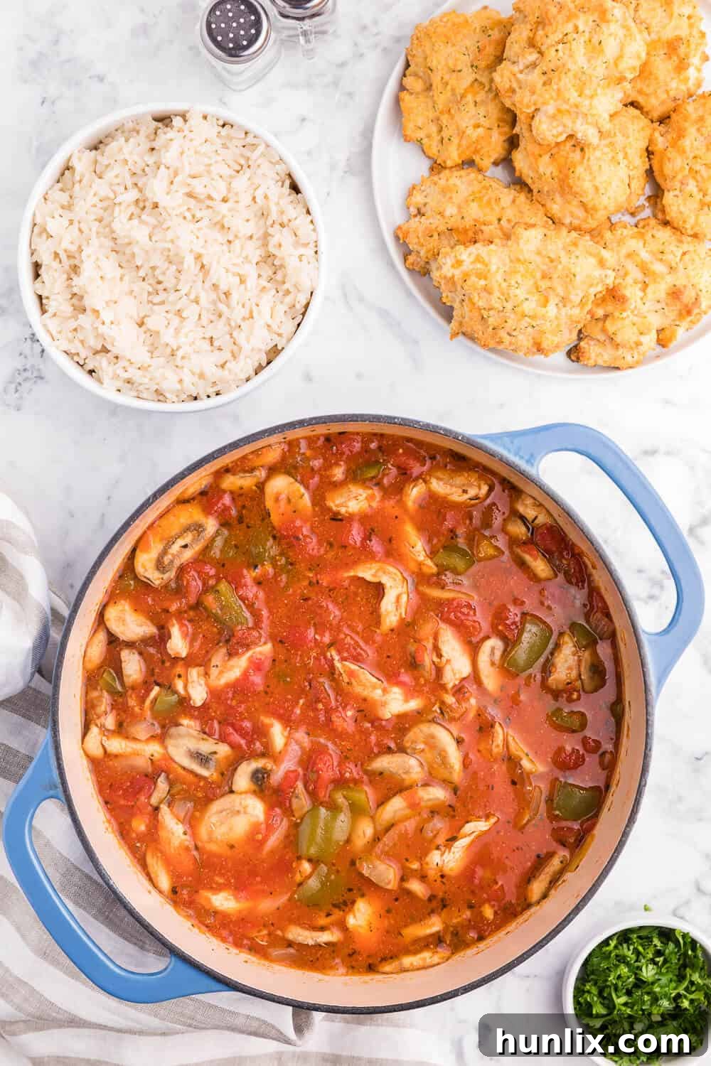 Close-up of tender chicken and vibrant vegetables simmering in tomato sauce in a Dutch oven for Chicken Cacciatore.