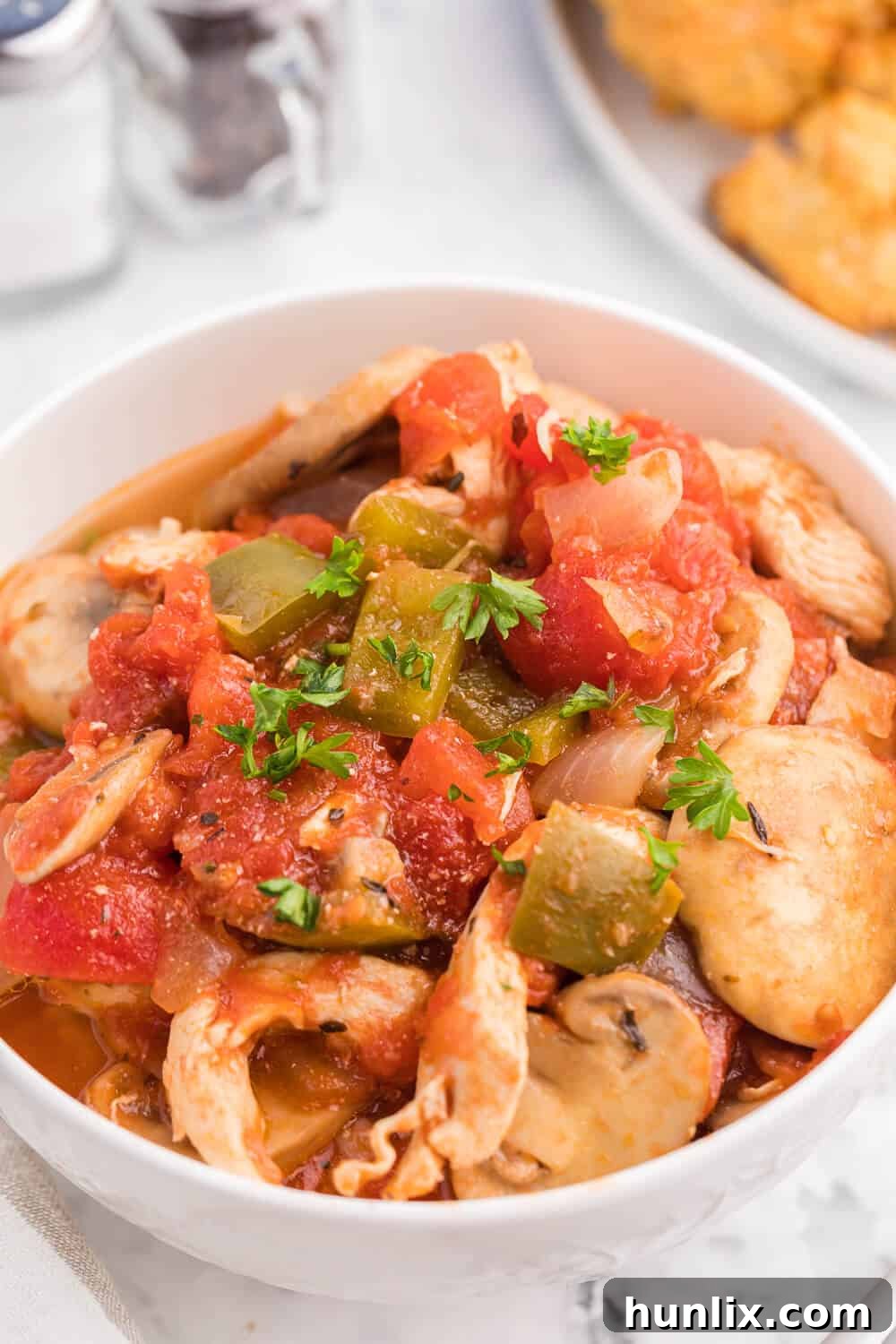A serving of One-Pot Chicken Cacciatore with pasta, garnished with fresh basil.