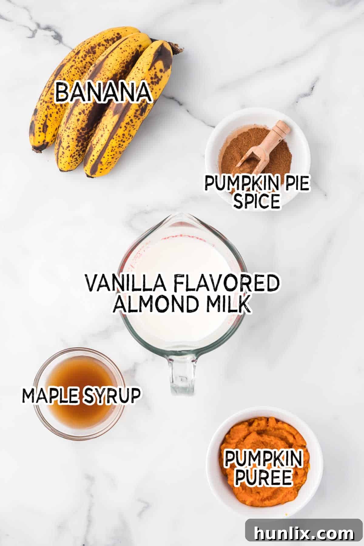 Velvet Pumpkin Sip 3 Collection of pumpkin pie smoothie ingredients laid out on a white marble countertop.