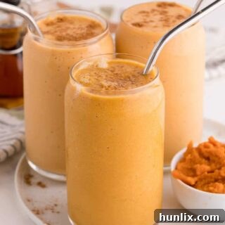 Three pumpkin pie smoothies on a plate.