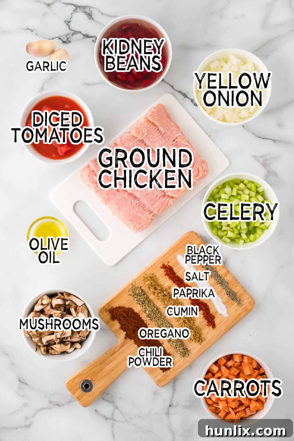 A collection of fresh ingredients laid out for making chicken chili, including ground chicken, vegetables, and spices.