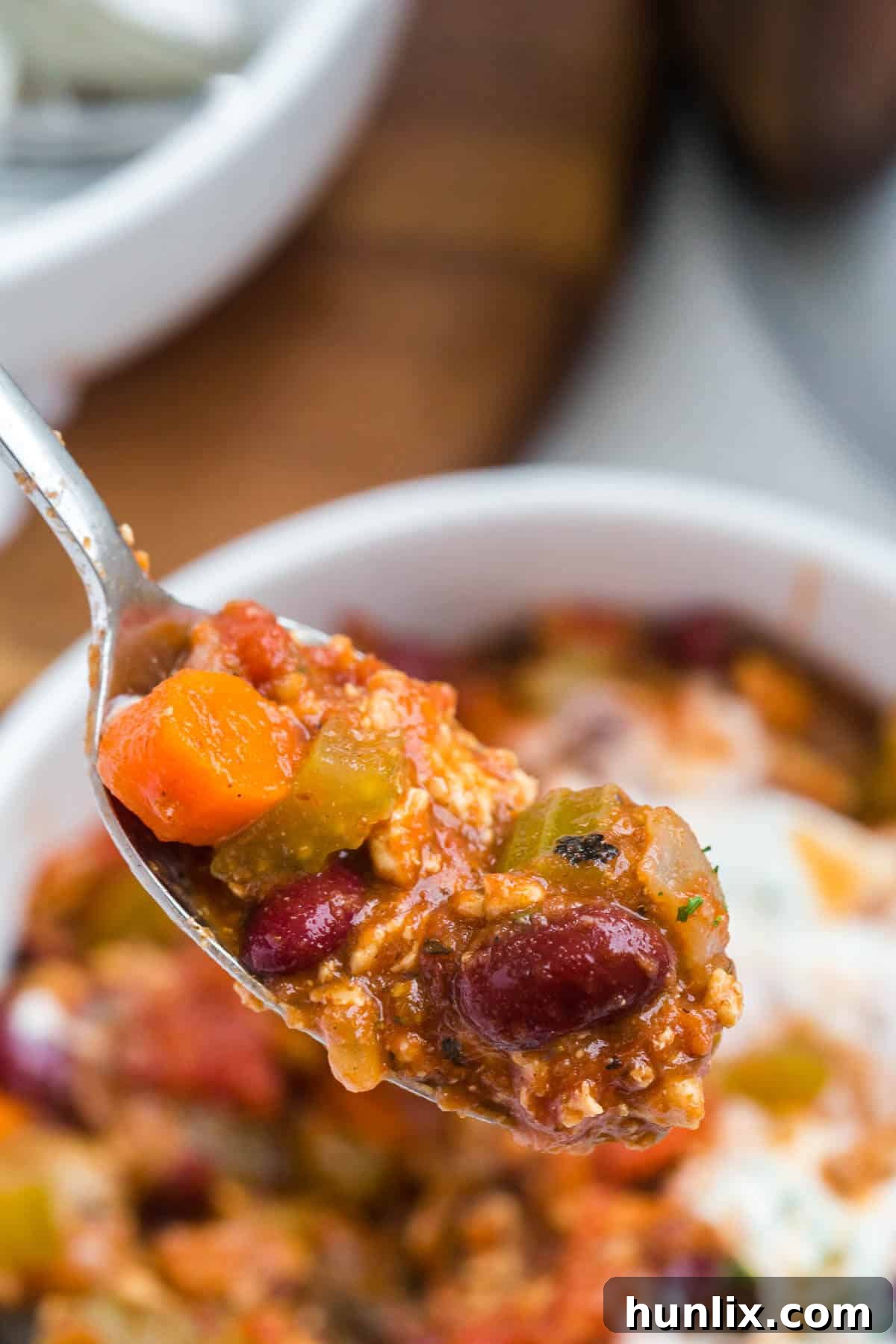 A spoonful of rich chicken chili, showcasing its hearty ingredients.