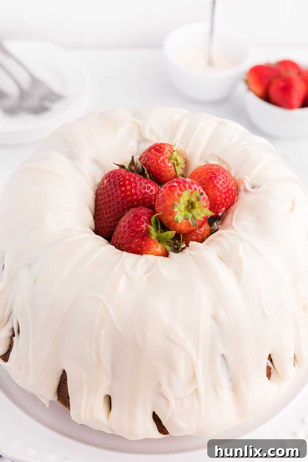 A whole Vanilla Cream Cheese Cake with fresh strawberries cascading down its sides.