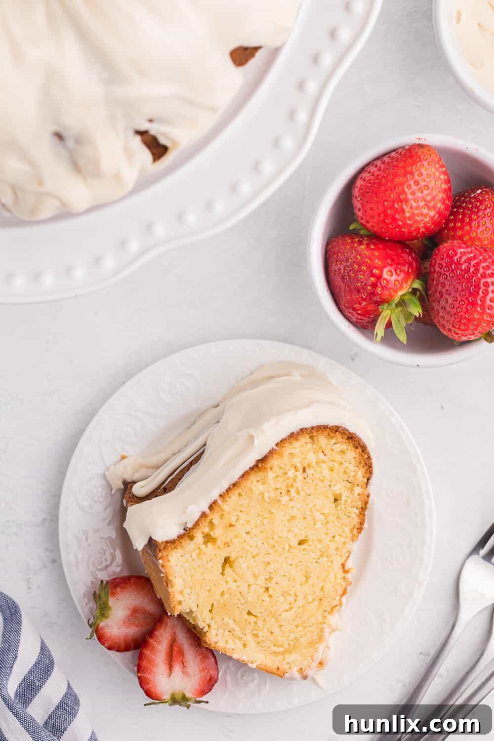 A perfectly baked slice of Vanilla Cream Cheese Cake, garnished with fresh strawberries and a drizzle of glaze.