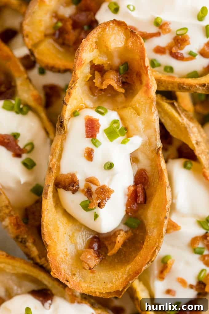 Cheesy Potato Skins - Topped with sour cream, tasty bacon and fresh green onions, this appetizer recipe is a crowd-pleasing classic.