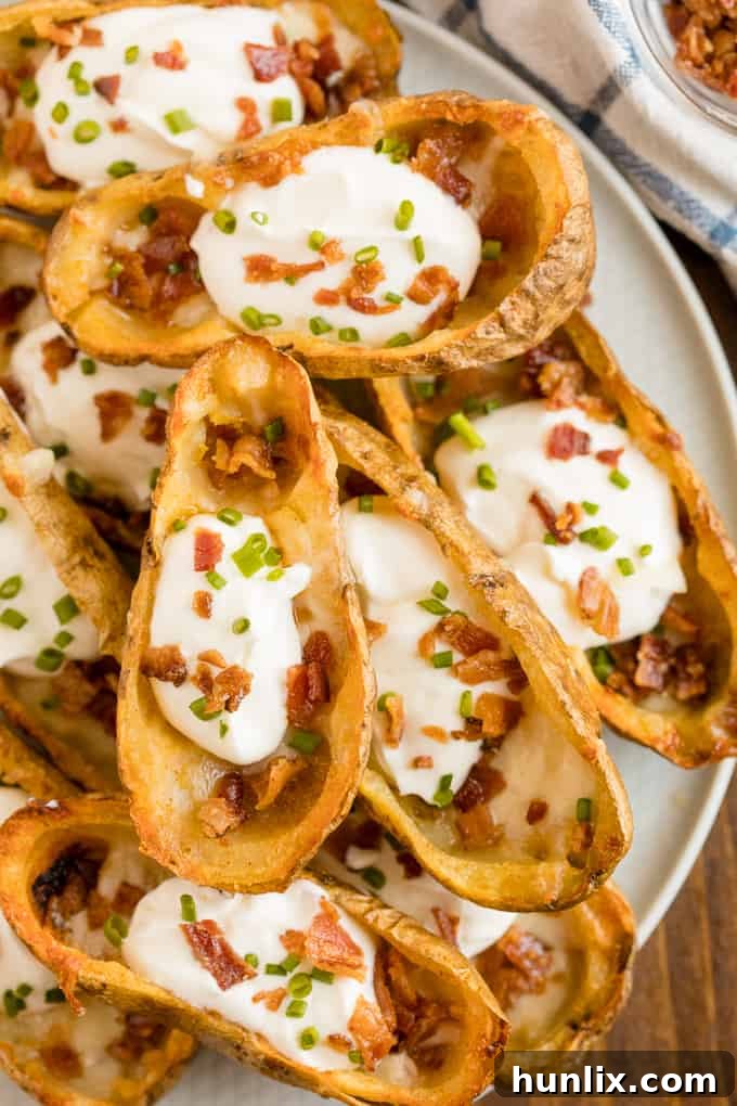 Cheesy Potato Skins - Topped with sour cream, tasty bacon and fresh green onions, this appetizer recipe is a crowd-pleasing classic.