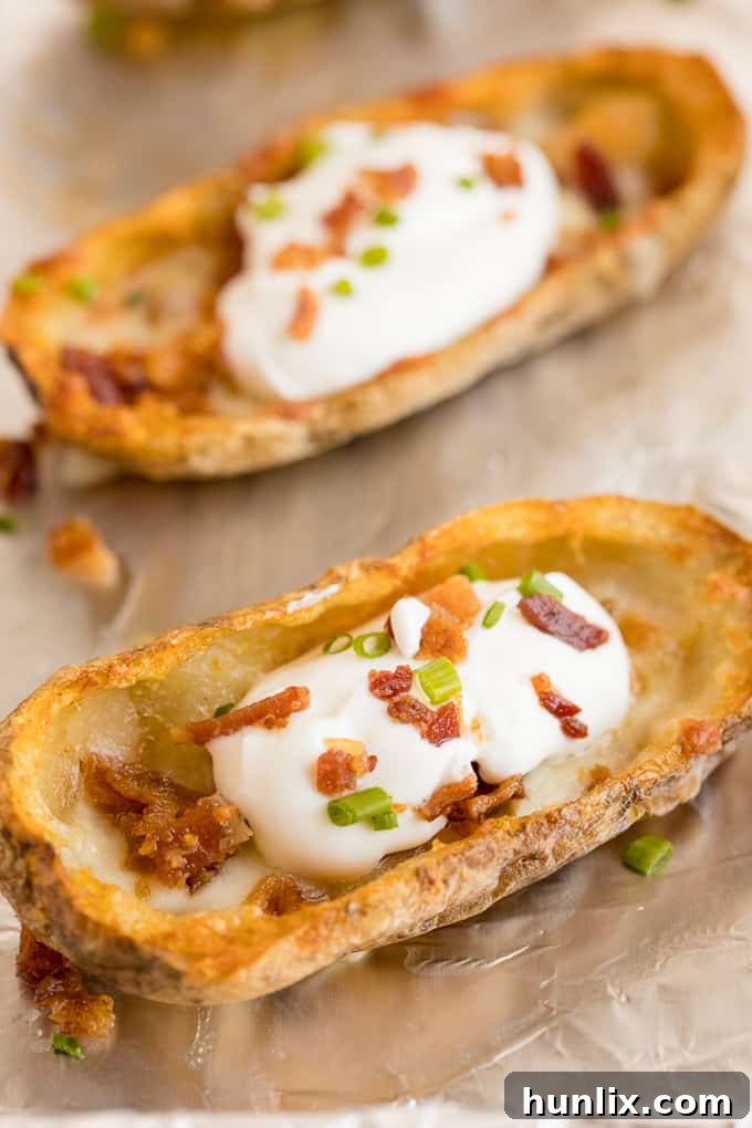 Cheesy Potato Skins - Topped with sour cream, tasty bacon and fresh green onions, this appetizer recipe is a crowd-pleasing classic.
