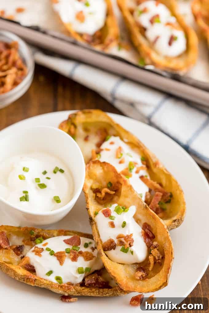 Cheesy Potato Skins - Topped with sour cream, tasty bacon and fresh green onions, this appetizer recipe is a crowd-pleasing classic.