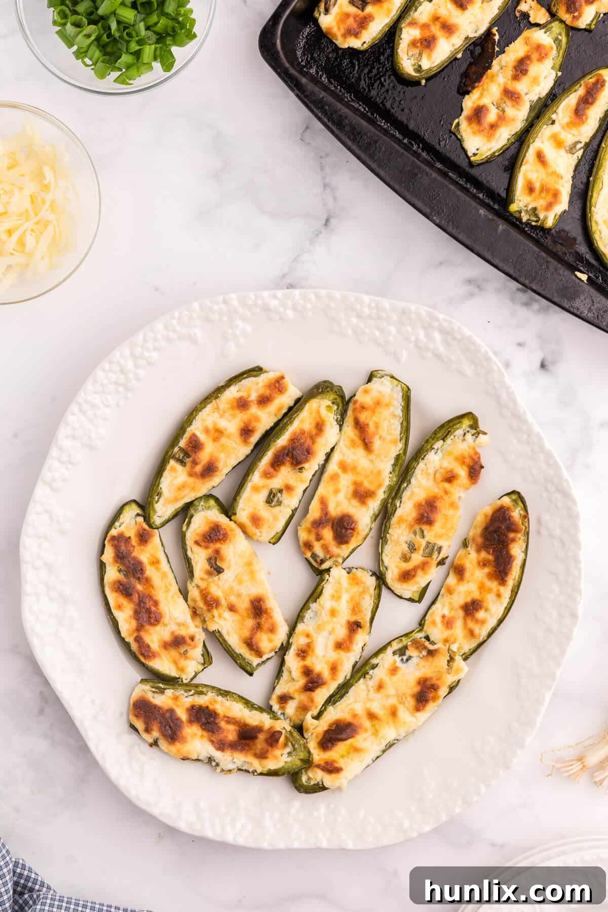A plate of golden-brown cream cheese stuffed jalapenos, garnished with fresh herbs.