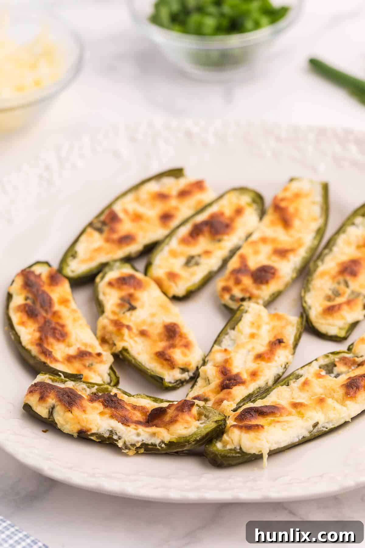 A vibrant plate of golden-brown cheese stuffed jalapenos, ready to be served at a party.