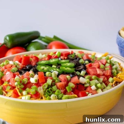 Mexican Layered Dip - A delightful seven-layered dip featuring refried beans, guacamole, salsa, and favorite toppings. Perfect party and game day food.