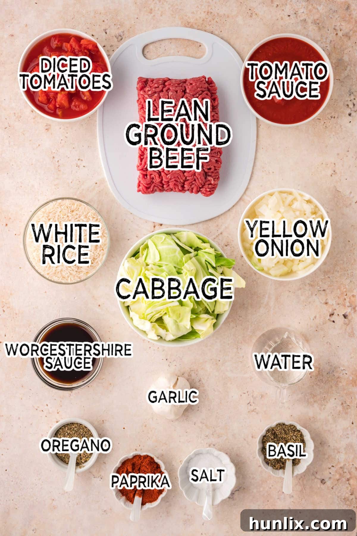 Fresh ingredients for Cabbage Roll Soup, including ground beef, chopped cabbage, tomatoes, onion, and spices, arranged on a beige background.