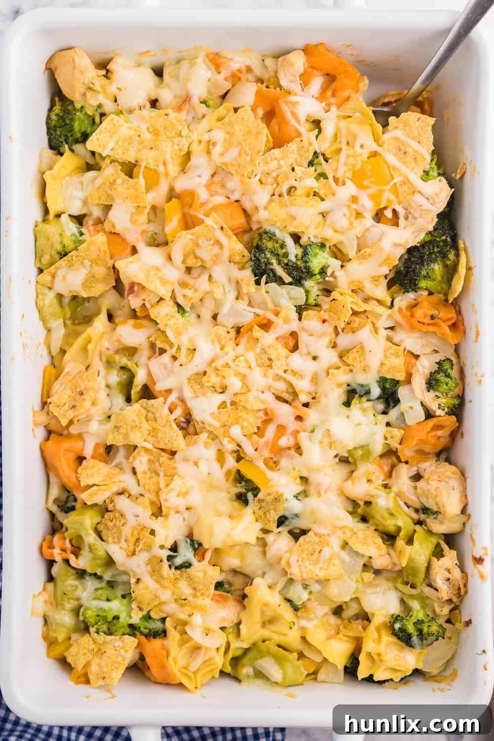 Santa Fe Chicken Tortellini Casserole - A close-up of creamy tortellini pasta with chicken and vegetables, topped with melted cheese and crunchy tortilla chips, ready to serve.